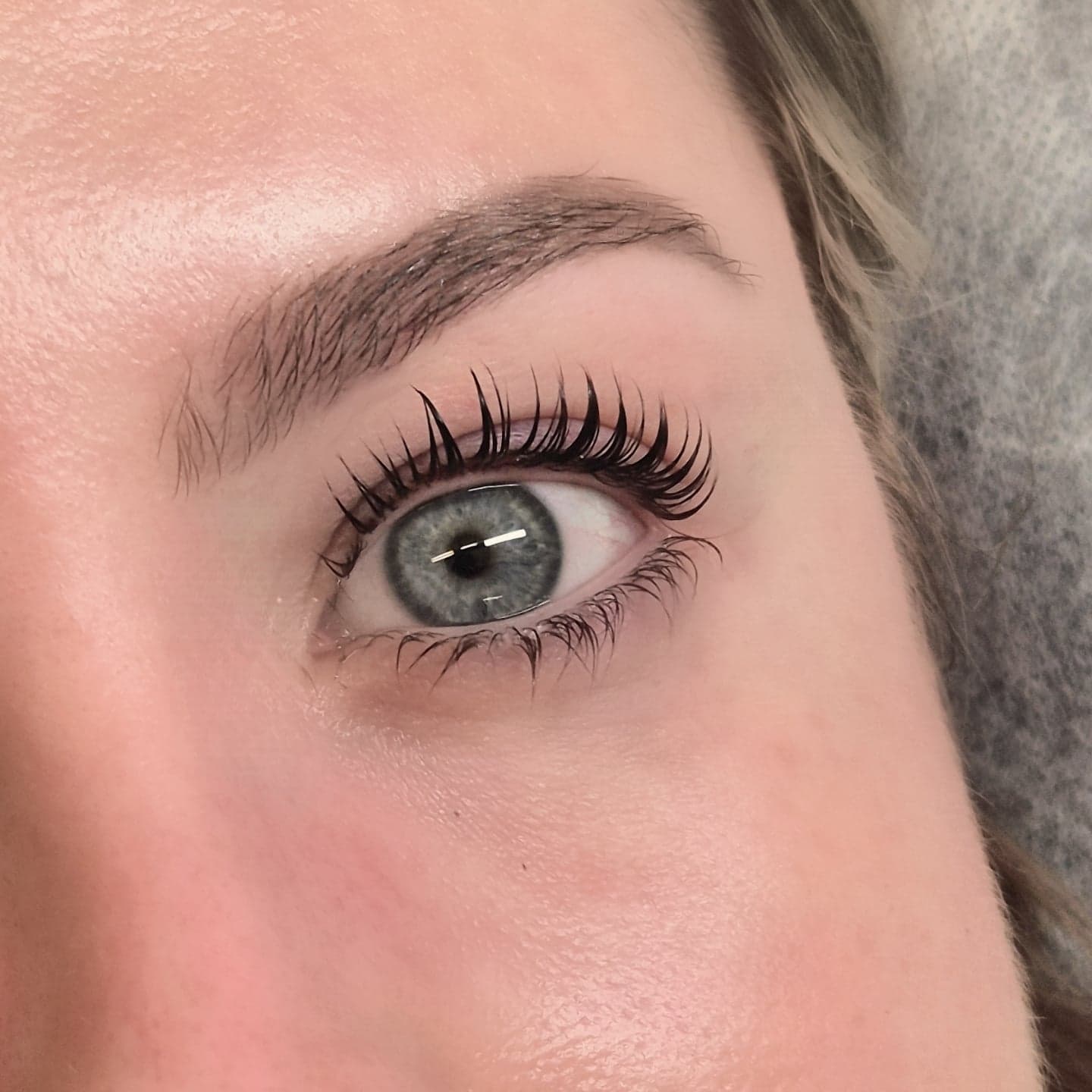 Lash lift with a defined natural brow on a blue eye