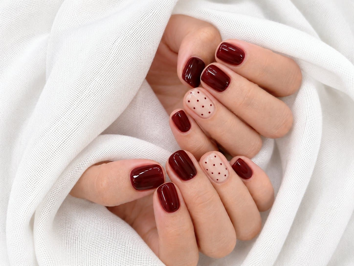Deep burgundy gel nails with polka dot accent nails