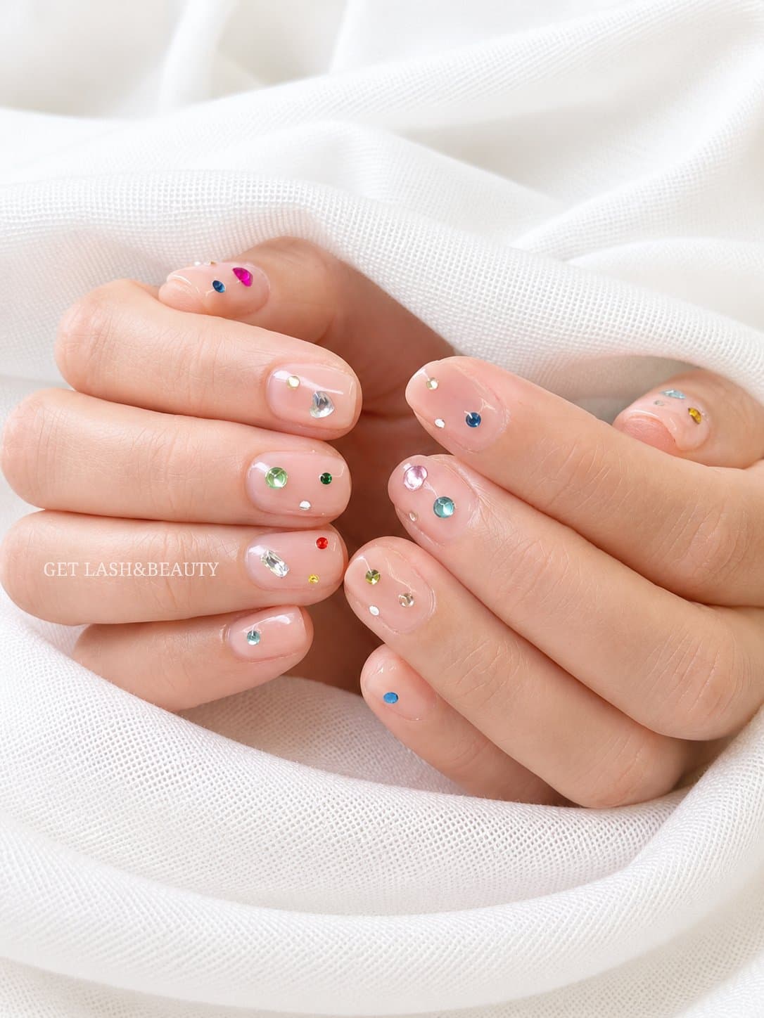 Natural gel nails with scattered coloured gem nail art